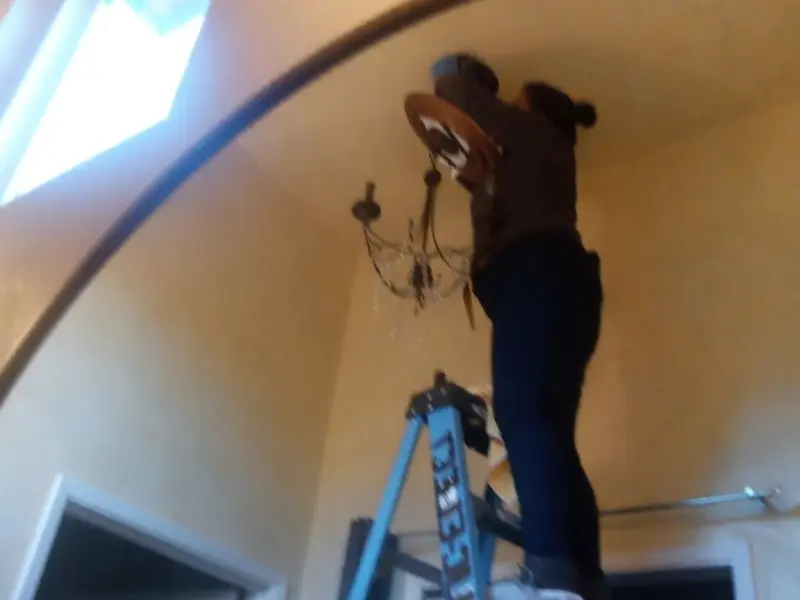 Electrician installing a chandelier in a Hayden residence